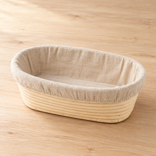Oval rattan sourdough banneton with fitted linen liner on natural timber