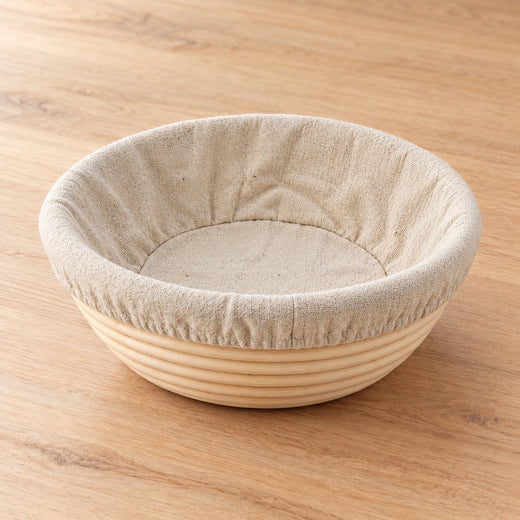 Round rattan sourdough banneton with fitted linen liner on natural timber