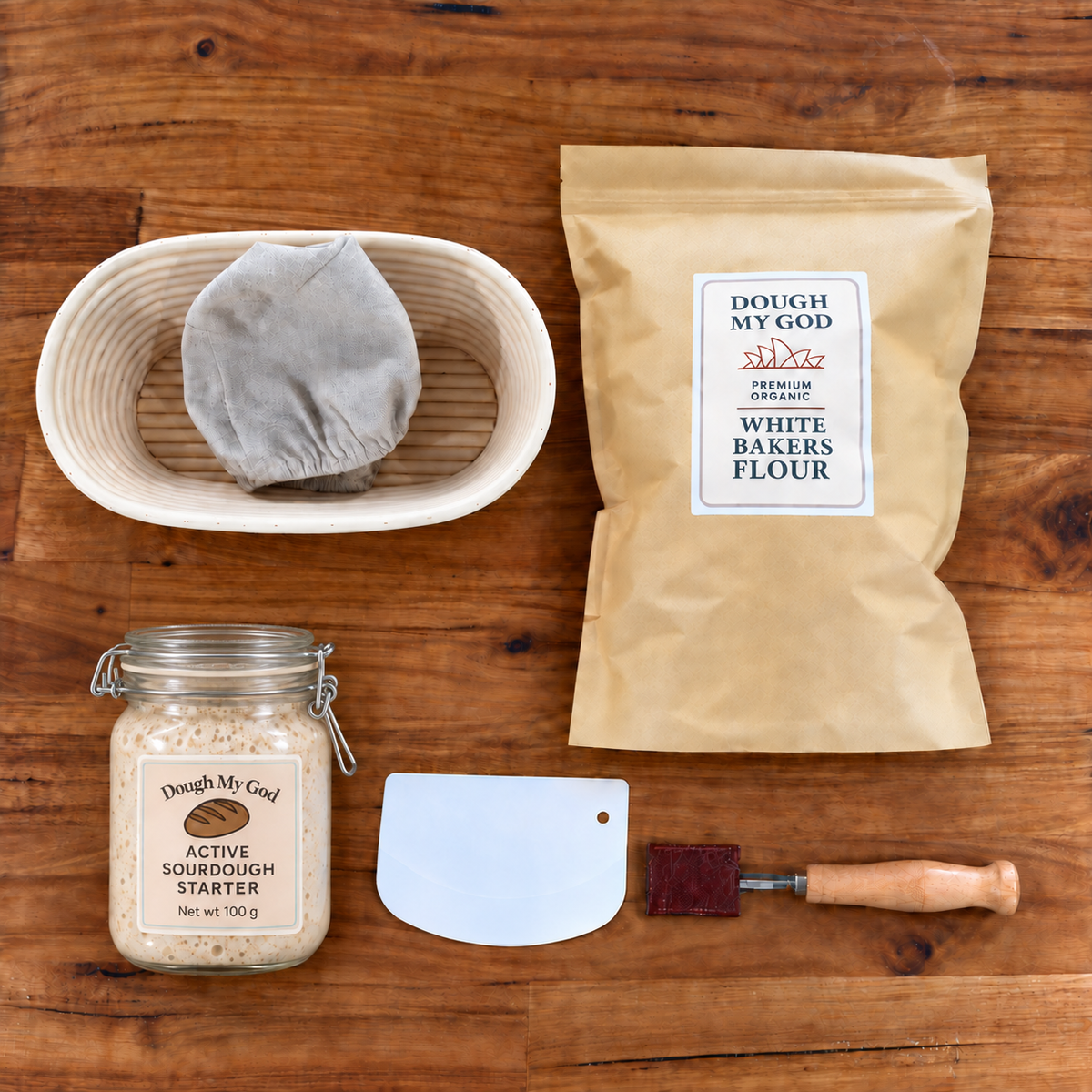 Essential sourdough starter kit with bubbling live starter in a closed-lid jar, organic bakers flour, oval banneton, dough lame and scraper