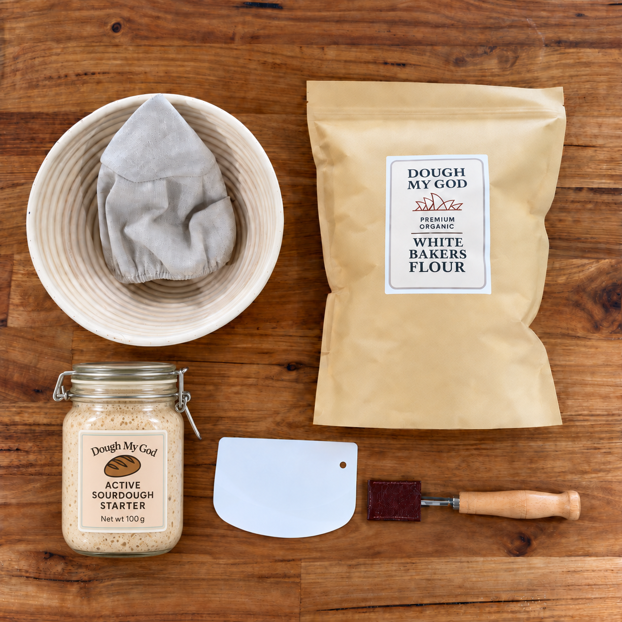 Essential sourdough starter kit with labelled bubbling live starter, organic bakers flour, round banneton, dough lame and scraper