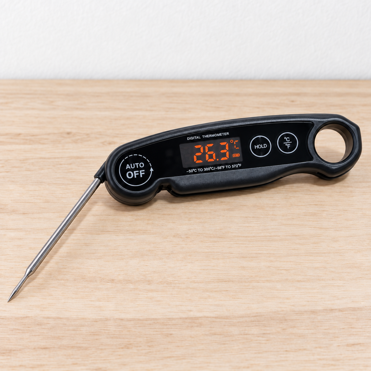 Black instant read digital food thermometer with open probe on a light timber bench